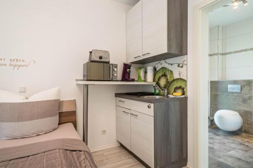 een kleine keuken met een wastafel en een magnetron bij Apartment mit Kaffeeküche für Zwei in Meersburg