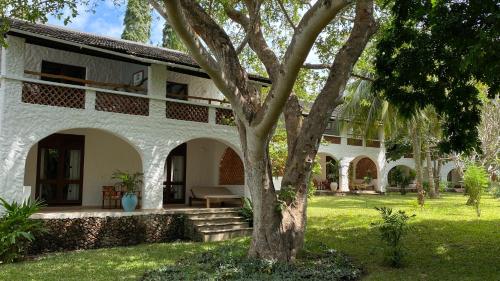a white house with a tree in the yard at Pinewood Beach Resort and Spa in Diani Beach