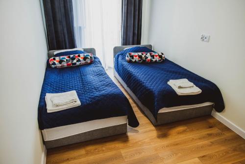 2 łóżka w pokoju z niebieską pościelą i poduszkami w obiekcie Młyńska 6H w mieście Zamość