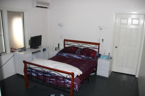 a bedroom with a bed and a flat screen tv at Star Inn Accommodation in Mount Isa