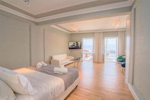 a bedroom with a white bed and a living room at THE YDRA VIEW APARTMENTS in Hydra