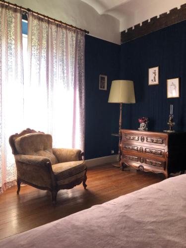 a bedroom with a chair and a bed and a dresser at Manoir de Champvert in Les Vans