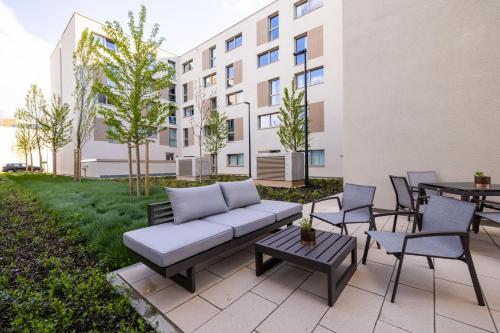 a patio with a couch and chairs and tables at MASEVEN München Messe Trudering in Munich