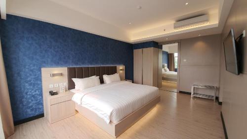a bedroom with a large bed and a blue wall at Classie Hotel in Palembang