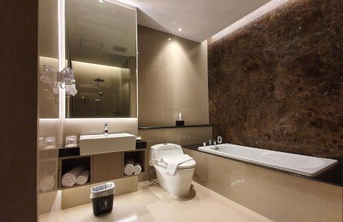 a bathroom with a toilet and a sink and a tub at Classie Hotel in Palembang