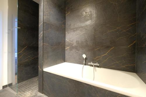 a bathroom with a bath tub and a sink at La Maison de la Duchesse de la Vallière - Chambre Rosaline - Parking privé gratuit in Mons
