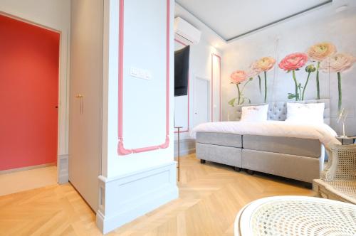 una camera da letto con un letto e fiori sul muro di La Maison de la Duchesse de la Vallière - Chambre Rosaline - Parking privé gratuit a Mons