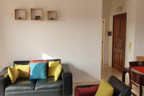 a black leather couch with colorful pillows in a living room at Santana double bedroom serviced apartment in Santa Maria