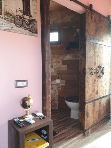 La salle de bains est pourvue de toilettes et d'une porte en bois. dans l'établissement Stanza Del Viggiatore, à Santadi