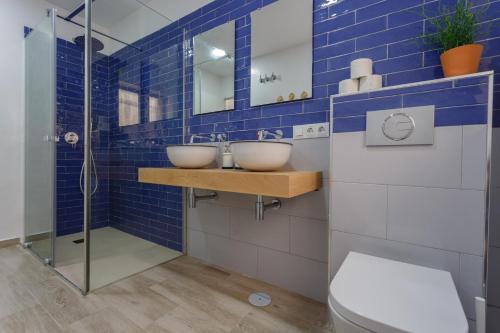 W wyłożonej niebieskimi kafelkami łazience znajdują się 2 umywalki i prysznic. w obiekcie TACITA Family Home by Cadiz4Rentals w Kadyksie