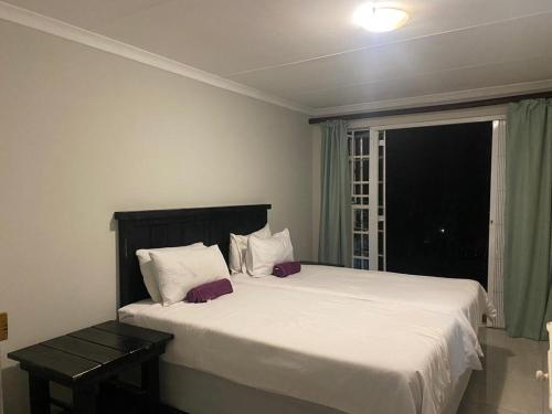 a bedroom with a large white bed and a window at Ndzuti Guest House in Witbank