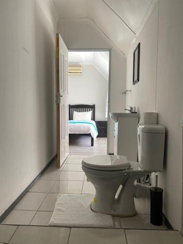 a white bathroom with a toilet and a bedroom at Ndzuti Guest House in Witbank