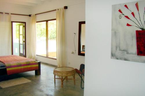 a bedroom with a bed and a chair and a window at VillaWatuna in Unawatuna