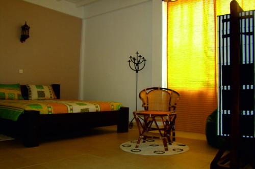 a bedroom with a bed and a chair and a window at VillaWatuna in Unawatuna