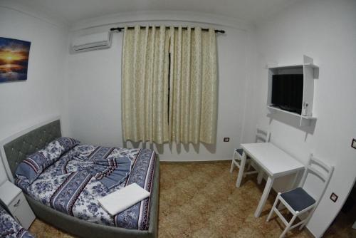 a bedroom with a bed and a desk and a television at Hotel Reci in Peshkopi