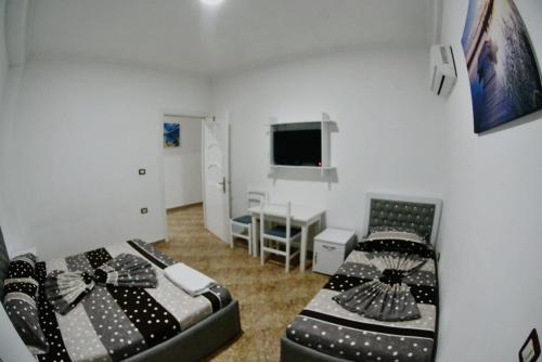 a bedroom with two beds and a desk and a television at Hotel Reci in Peshkopi
