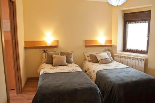 two beds in a small room with a window at La casa del rebote in Acedo