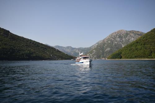a white boat on the water with mountains in the background at Apartment by the Sea in Tivat