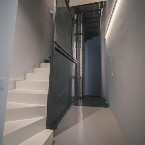 a hallway with white stairs and a black door at Palazzo Paladini - Luxury Suites in the Heart of the Old Town in Pizzo