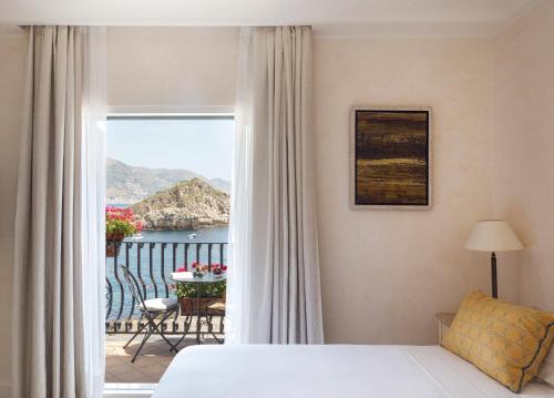 a bedroom with a bed and a view of a balcony at Villa Sant'Andrea, A Belmond Hotel, Taormina Mare in Taormina