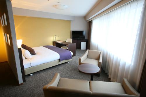une chambre d'hôtel avec un lit et une chaise dans l'établissement Daiwa Roynet Utsunomiya, à Utsunomiya