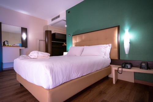 a bedroom with a large bed with a green wall at UNA HOTELS MH Matera in Matera