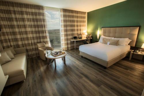 a hotel room with a bed and a couch at UNA HOTELS MH Matera in Matera
