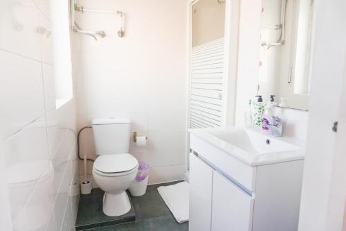 a white bathroom with a toilet and a sink at Hospedium Hostel República Surf House in Ericeira