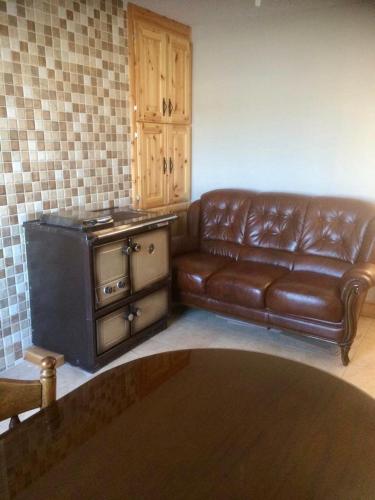 a living room with a brown leather couch and a stove at Kathleen’s Haven in Causeway