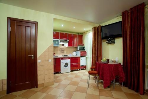 eine Küche mit roten Schränken und einem Tisch darin in der Unterkunft Hotel Nataly on Srednemoskovskaya 7 in Woronesch