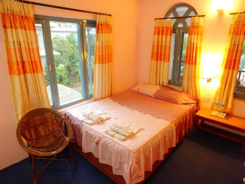 a bedroom with a bed with yellow curtains and a window at Hotel Greenland in Pokhara