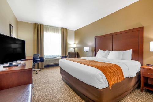 a hotel room with a large bed and a flat screen tv at Comfort Inn Near UNT in Denton