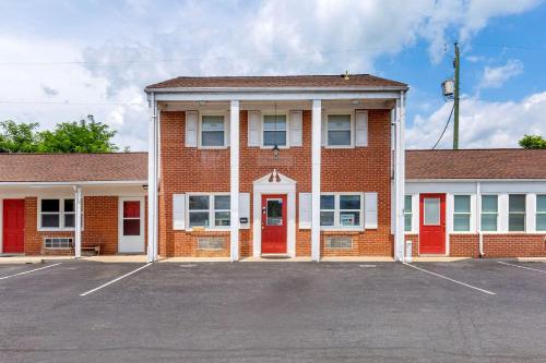 a brick building with red doors and a parking lot at Econo Lodge Woodstock - Shenandoah Valley I-81 in Woodstock