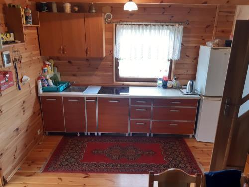 uma cozinha com armários de madeira e um frigorífico em Domek w Kwiatach em Mrągowo