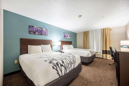 a hotel room with two beds and a desk at Sleep Inn & Suites in Birmingham
