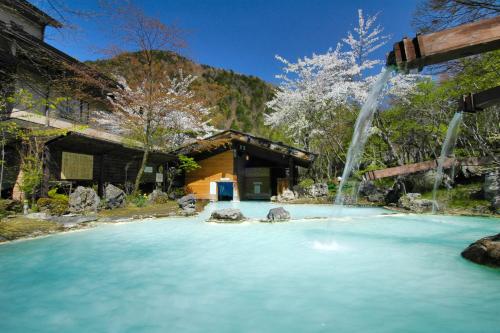una piscina de agua con una fuente frente a una casa en Awanoyu, en Matsumoto
