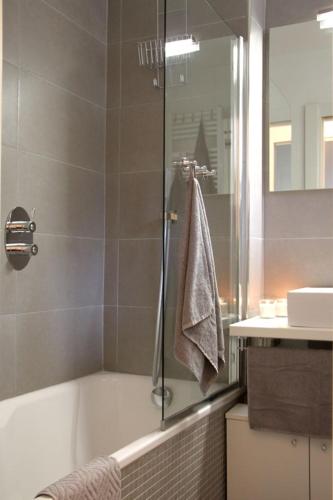 a bathroom with a tub and a shower with a towel at Pinzolo Wellness Apartment in Pinzolo