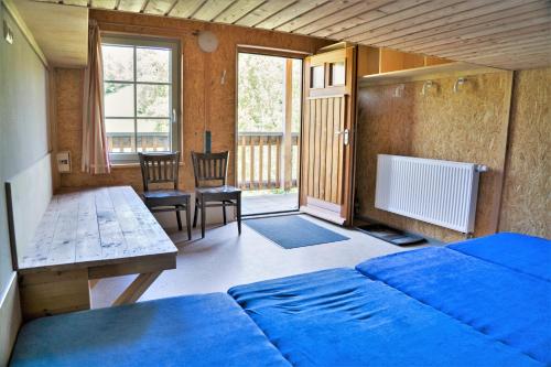 Schlafzimmer mit einem blauen Bett, einem Tisch und Stühlen in der Unterkunft "Ottendorfer Hütte" - Bergwirtschaft in Kirnitzschtal