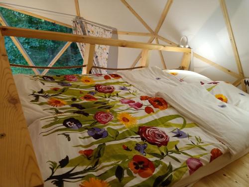 a bed with a floral comforter in a room at Młyn Hipolit glamping in Nowy Gaj