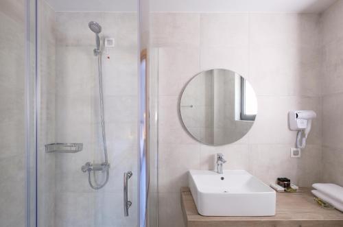 a bathroom with a sink and a shower with a mirror at Margo Beach Hotel in Gythio