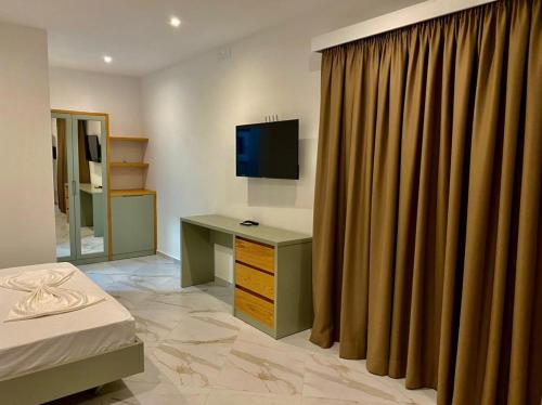 ein Schlafzimmer mit einem Schreibtisch, einem TV und einem Vorhang in der Unterkunft Domi Beach Valley in Dhërmi