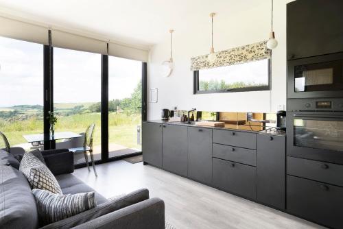 a living room with a couch and a kitchen with windows at Box6 at West Down in Sherborne