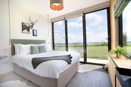 a bedroom with a large bed and a large window at Box6 at West Down in Sherborne