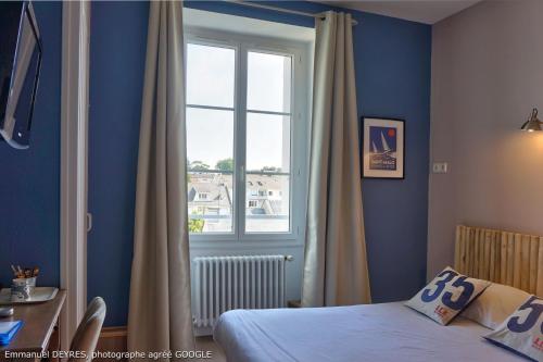 a bedroom with a bed and a window and a desk at Queen Serenity Hotel in Redon