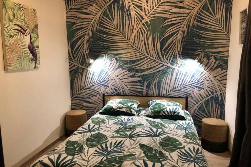 1 dormitorio con 1 cama con papel pintado tropical en Laon : Suite privée au pied de la cathédrale, en Laon
