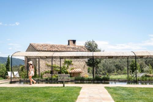 a woman walking in front of a building at ECOTurisme Can Buch HOTEL in Sant Aniol de Finestras