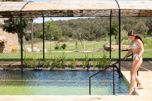 a woman in a bikini standing in a swimming pool at ECOTurisme Can Buch HOTEL in Sant Aniol de Finestras