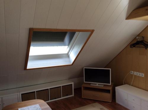 a attic room with a window and a television at Ferienwohnung A&K in Bottrop
