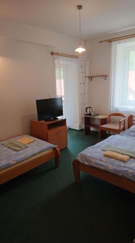 a room with two beds and a flat screen tv at Penzion pod Vlkolíncom in Ružomberok