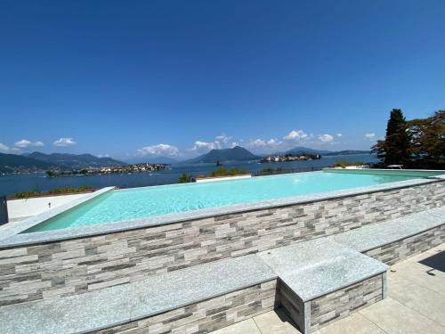 a swimming pool with a stone wall and water at Amadeus in Baveno